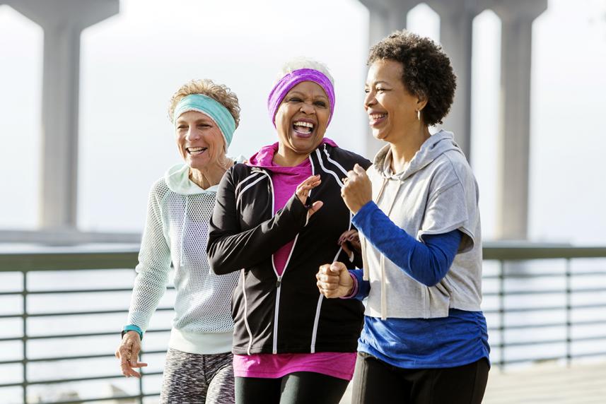 A group of 3 women walking outside together, laughing