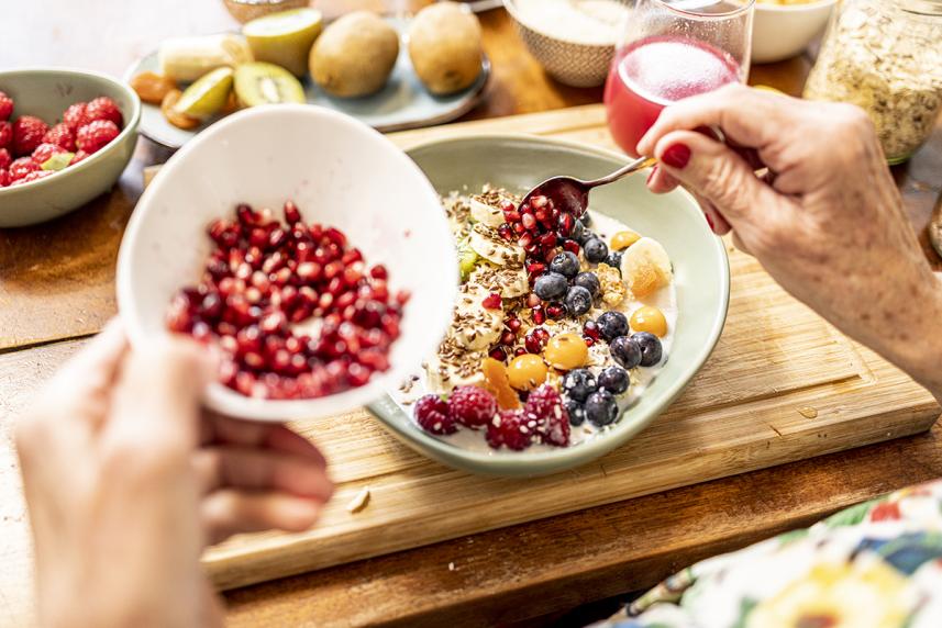 Hands of older woman stirring fresh fruit into a bowl of oatmeal